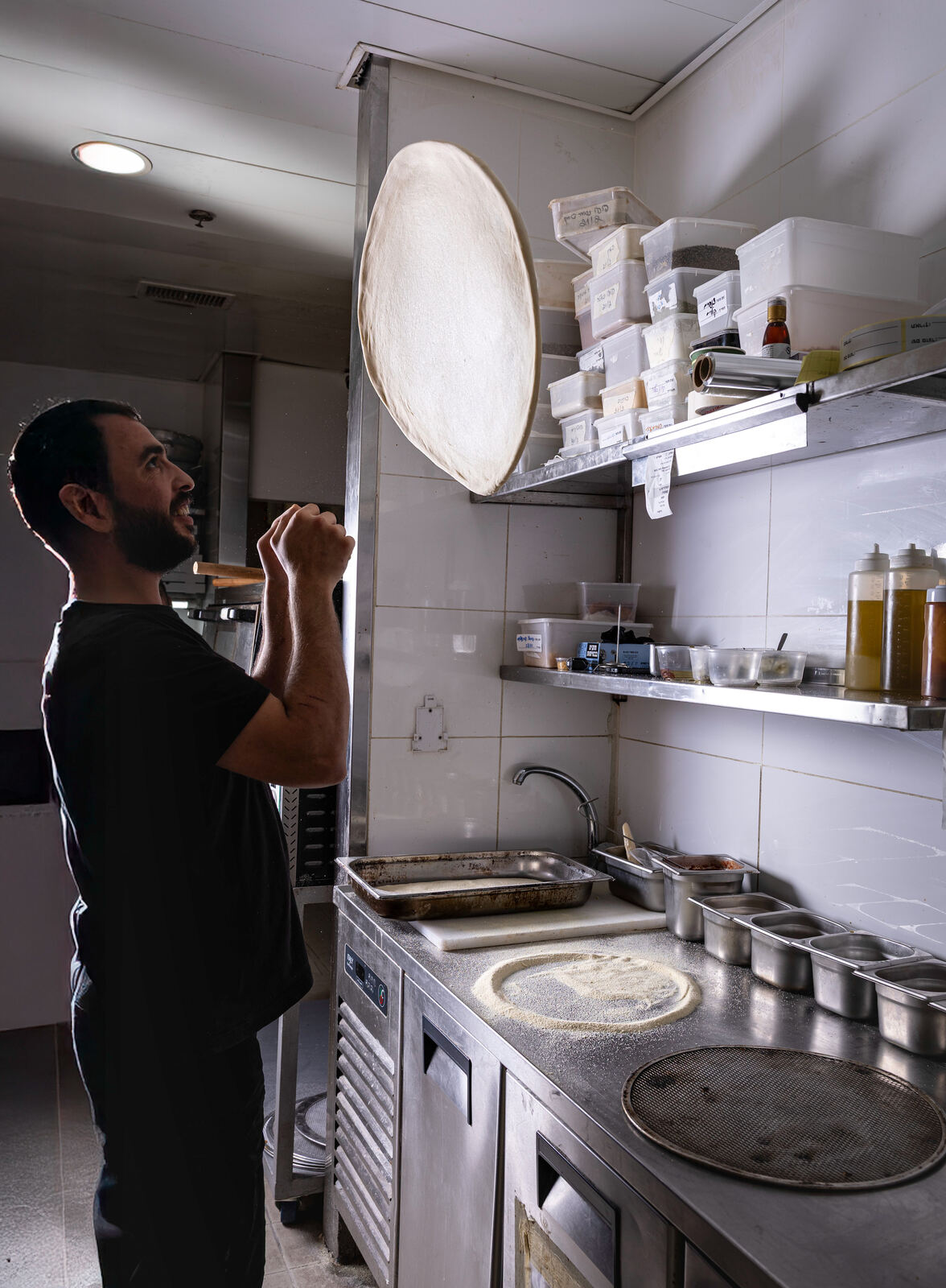 שף מרים בצק פיצה במטבח